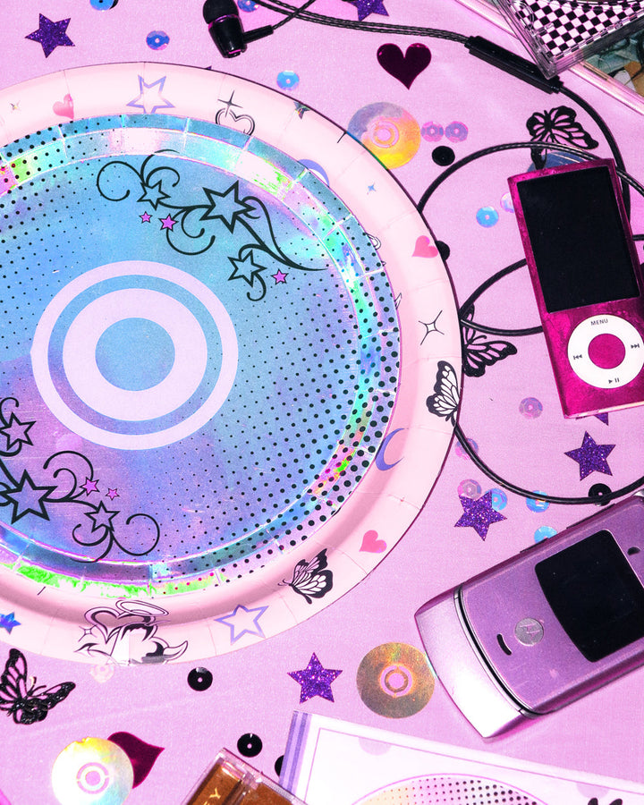Iridescent foil CD dessert plate with tattoo-style stars beside a flip phone and earbuds