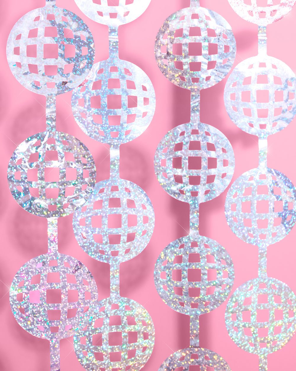 Layered silver disco ball cutouts on a curtain backdrop against a pink wall