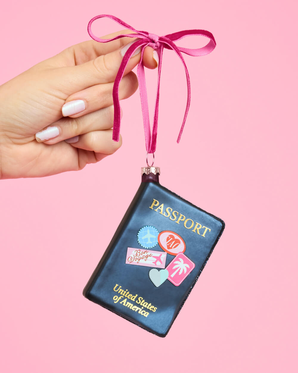 Additional view of the navy passport travel ornament and its bright pink ribbon hanger.