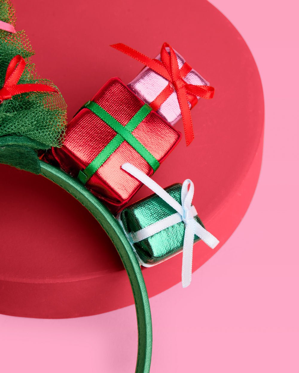 Detail of tiny metallic red, blue, and green wrapped gift boxes at the base of the headband tree