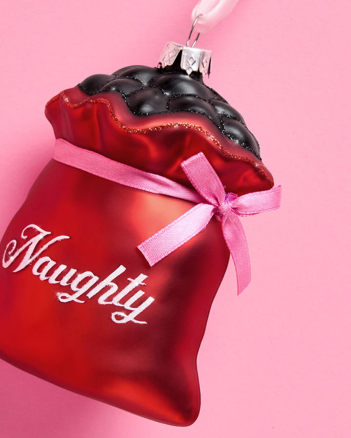 The Naughty and Nice glass ornament set shown again, with pink satin bow accents on the pink velvet hangers.