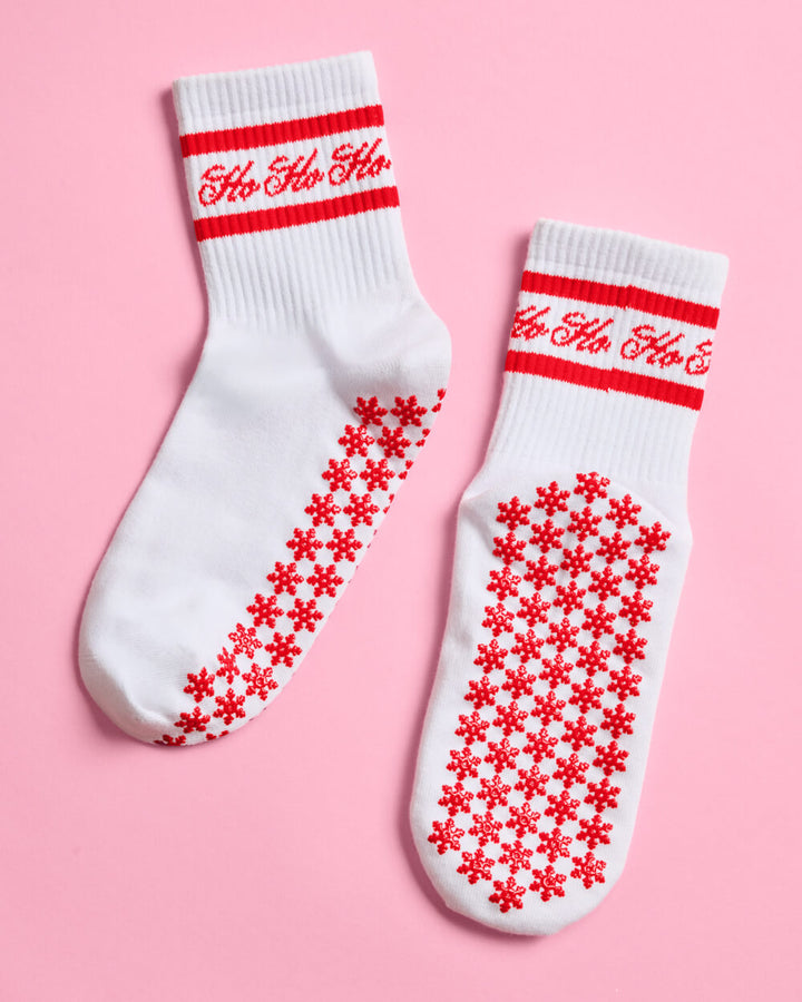 A pair of Christmas pilates grip socks showing the Ho Ho Ho script and the red snowflake sole