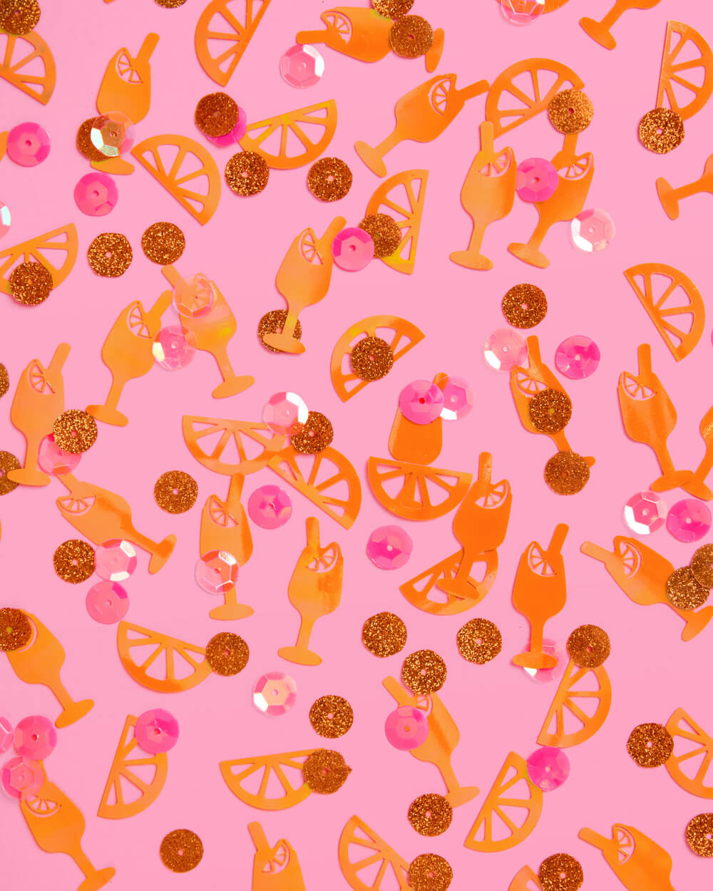 Close-up pattern of orange spritz cocktail and citrus confetti with gold glitter and pink sequins