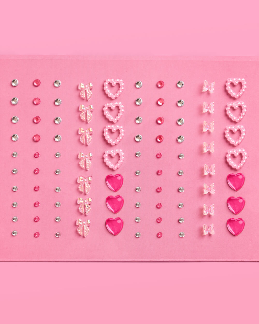 Pink heart-shaped face and sticker gems on a pink background