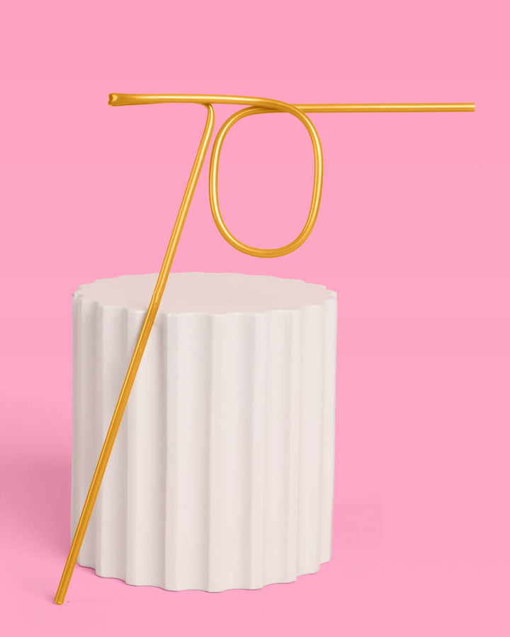 Gold 70 straw in a champagne flute on a pink background