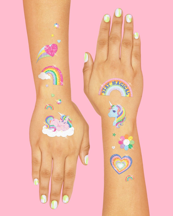 Arm and hand with glitter rainbow, heart, shooting star, and unicorn tattoos, a unicorn birthday party favor