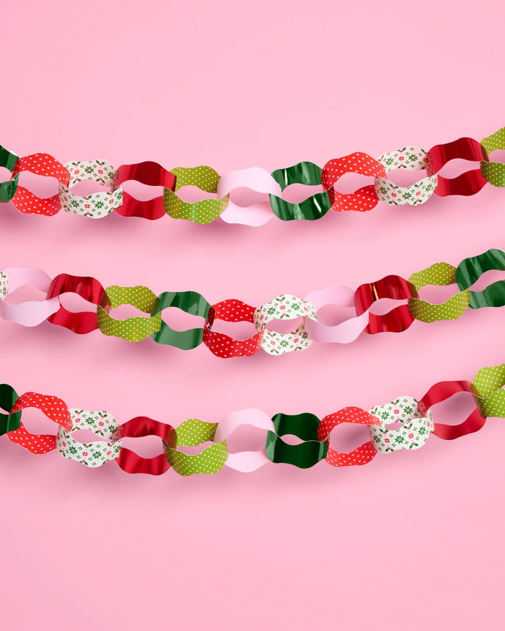 Three strands of printed paper chain garland in red, green, pink, and cream