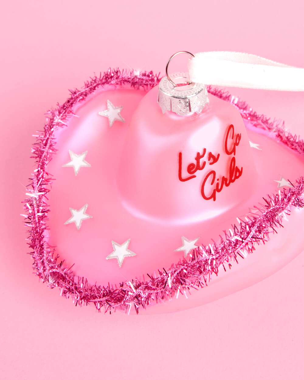 Close-up of the pink cowgirl hat ornament with silver glitter stars, pink tinsel brim, and red Let's Go Girls script