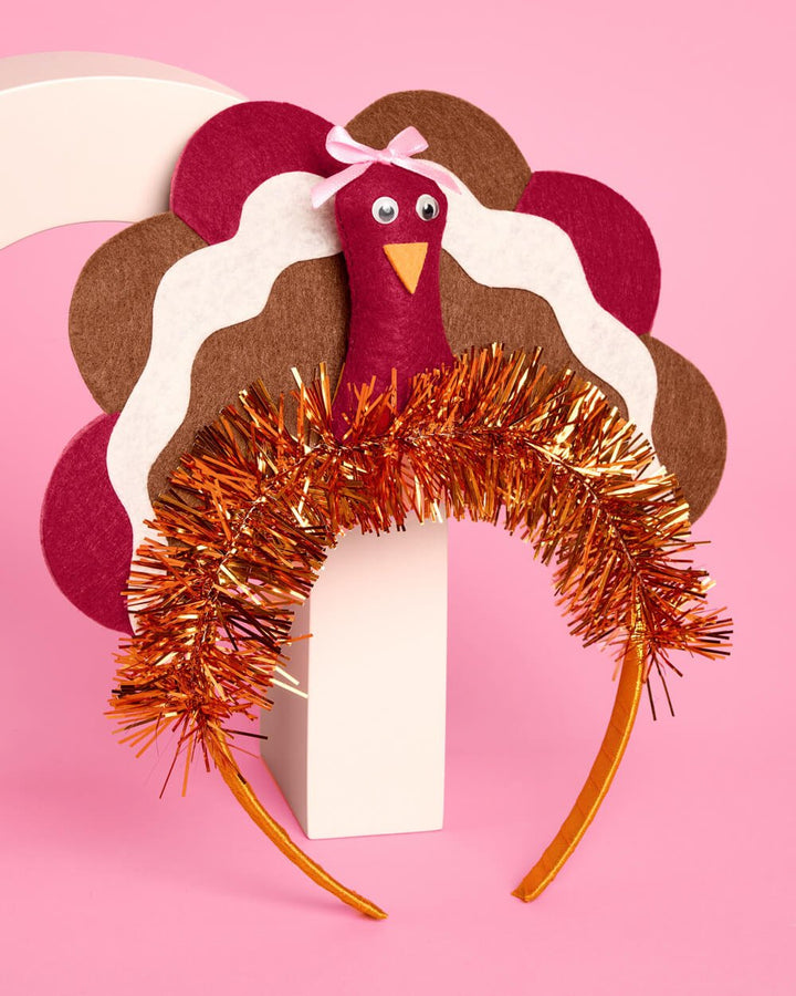 Turkey headband with burgundy, cream, and tan felt feathers on a pink background