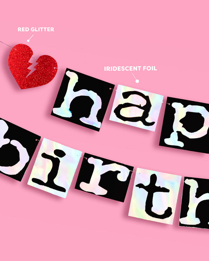 Close-up of iridescent foil letters on black tiles and a red glitter broken heart on the emo birthday banner
