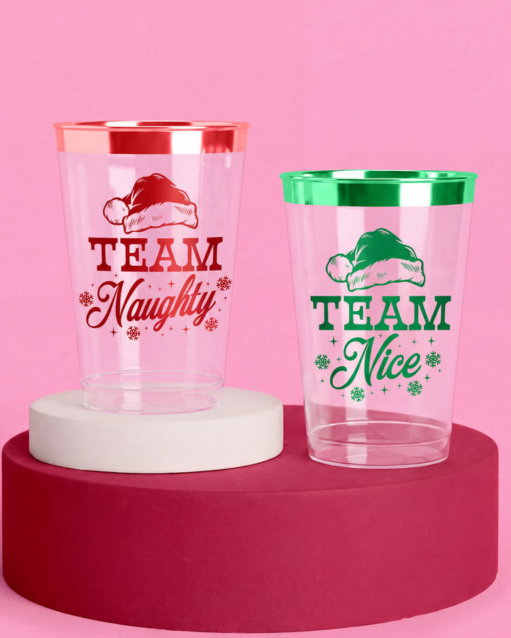 Team Naughty and Team Nice plastic Christmas cups with Santa hat prints on a pink background