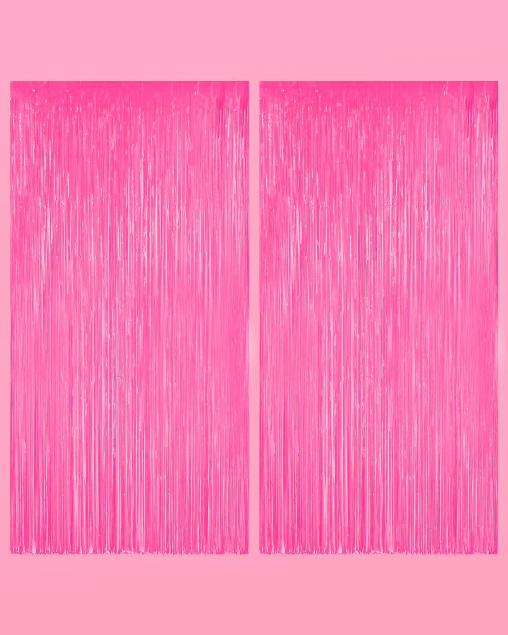 Two neon pink fringe curtain panels hung side by side on a pale pink wall