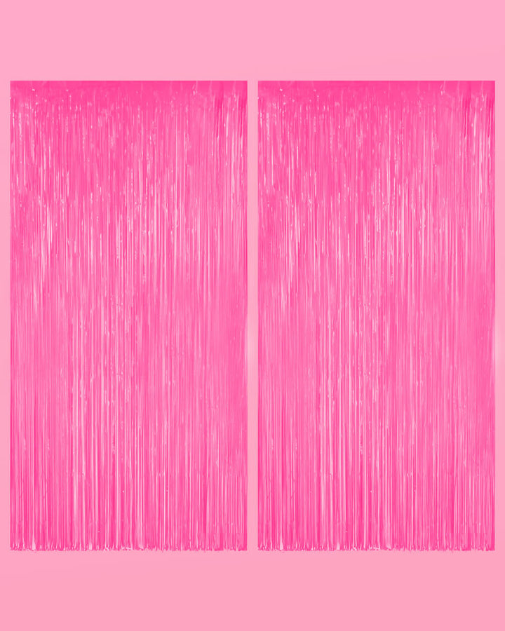 Two neon pink fringe curtain panels hung side by side on a pale pink wall