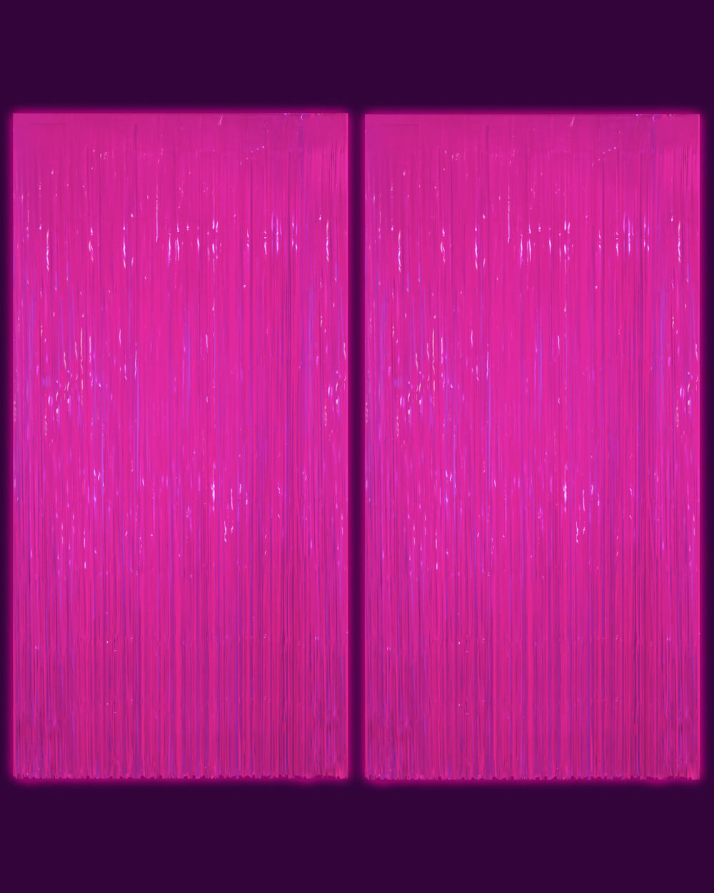 Two neon pink fringe curtain panels photographed in a dark room glowing magenta