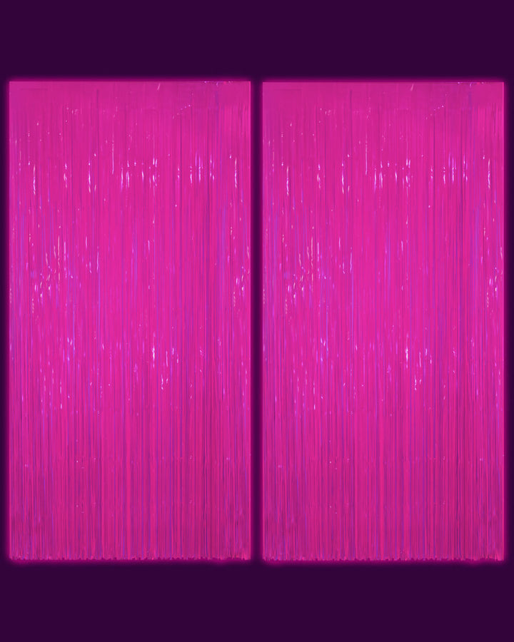 Two neon pink fringe curtain panels photographed in a dark room glowing magenta