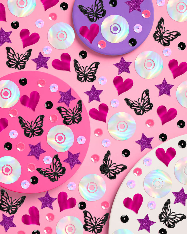 Y2K foil confetti in pink hearts, purple stars, black butterflies, and iridescent CDs on pink plates