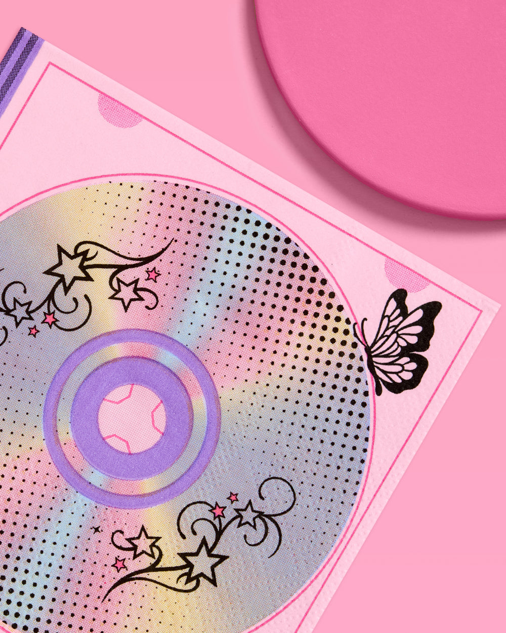 Close-up of an iridescent CD and black butterfly print on a Y2K paper cocktail napkin