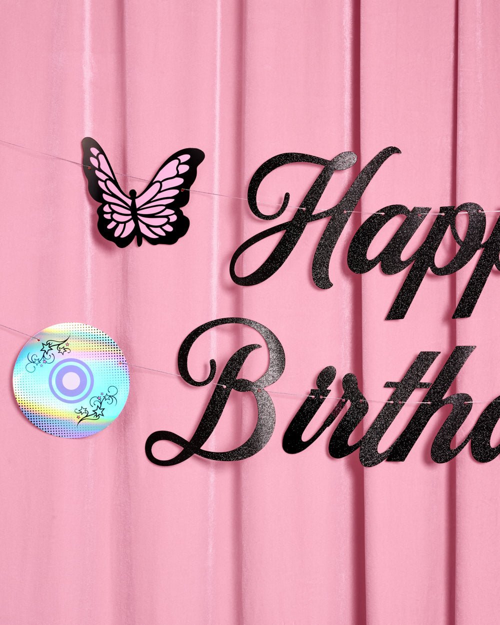 Black glitter Happy Birthday script with a butterfly and CD icon on the Y2K banner hung on a pink wall