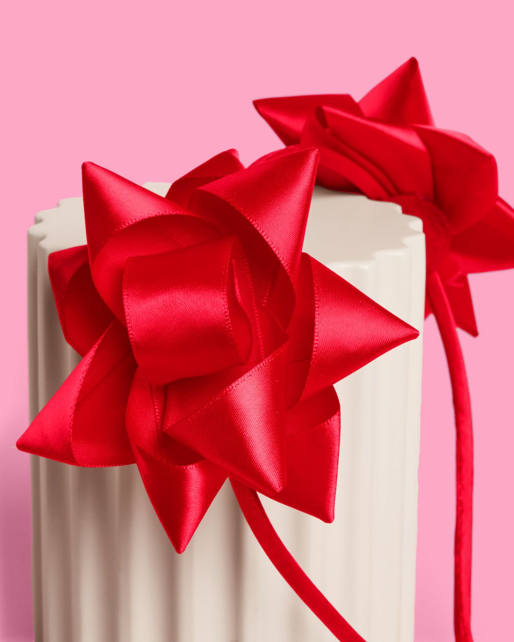 Close-up of a red satin gift bow on the headband, folded loops like a present topper