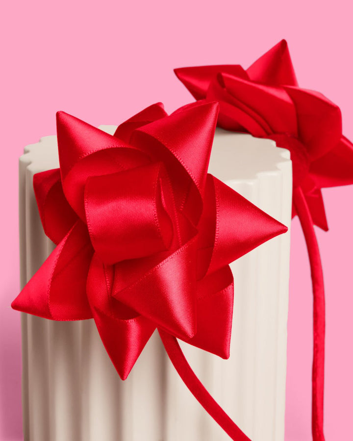 Close-up of a red satin gift bow on the headband, folded loops like a present topper