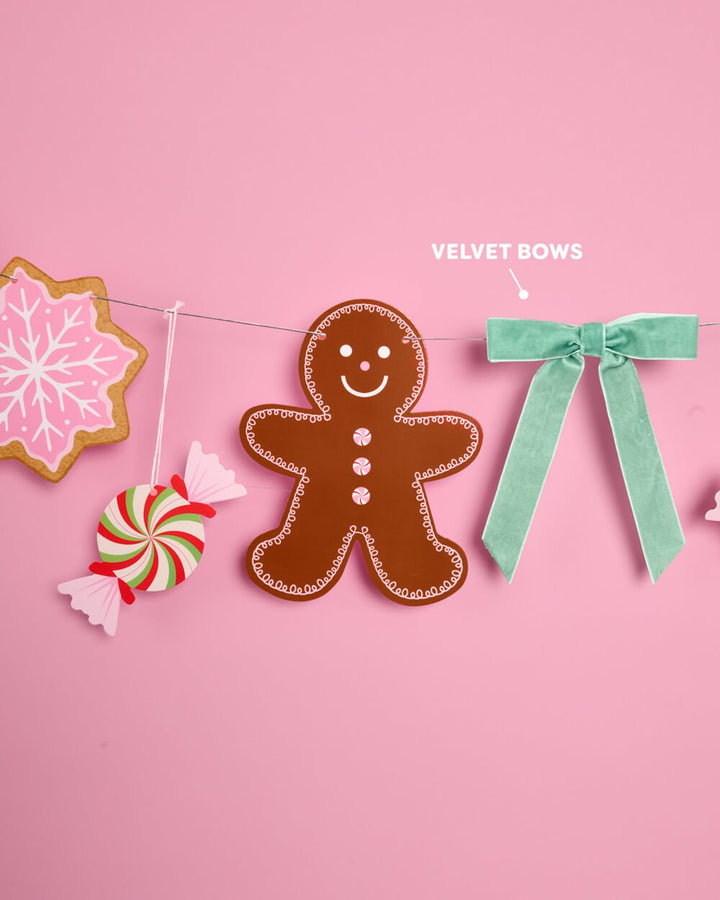 Close view of a gingerbread cookie icon and a light green velvet bow on the garland