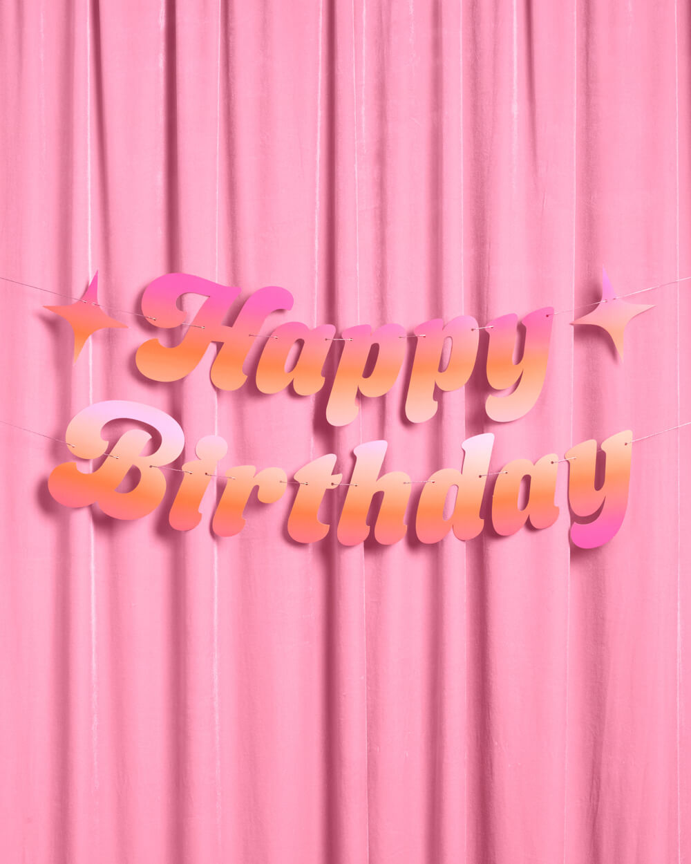 Pink and orange Happy Birthday banner with sparkle stars hung on a pink velvet backdrop