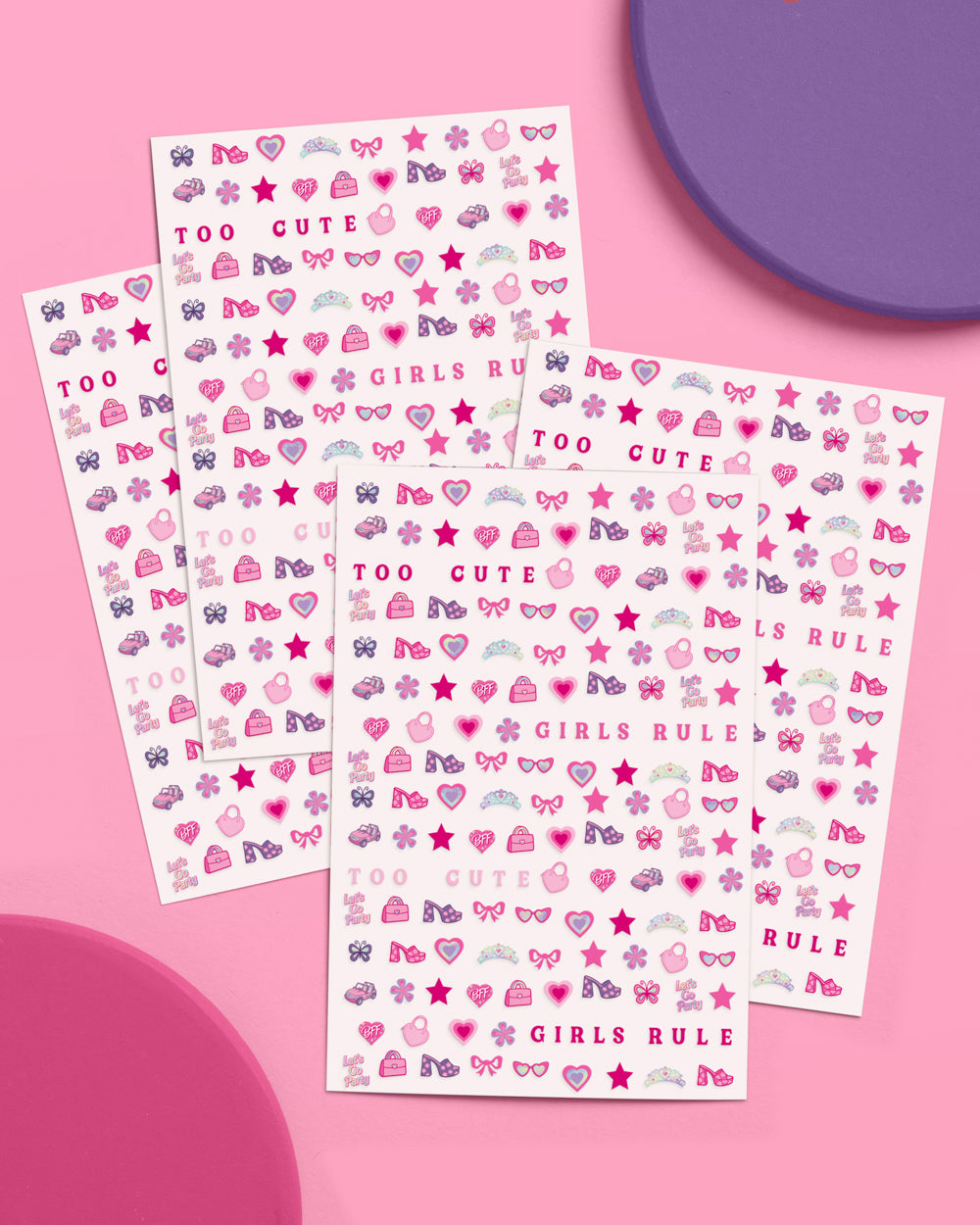 Four sheets of pink party nail art stickers fanned out on a pink and purple background