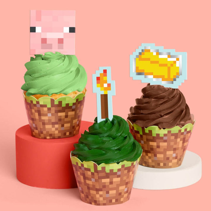 Pixel mining cupcake set by xo Fetti with grass-block wrappers and pixel toppers including a pig, torch, and gold bar