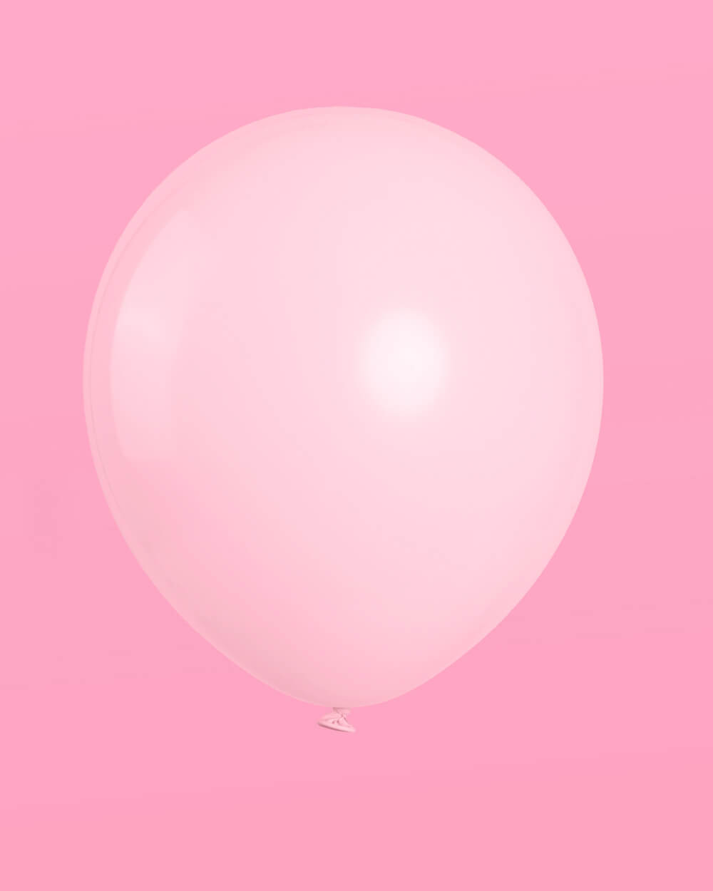 Single macaron pink latex balloon on a pink background