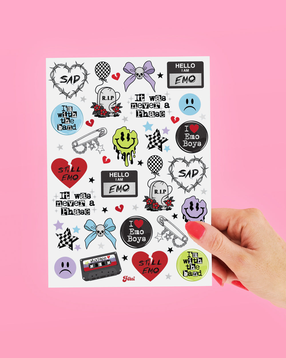 Hand holding a sheet of emo foil temporary tattoos against a pink background