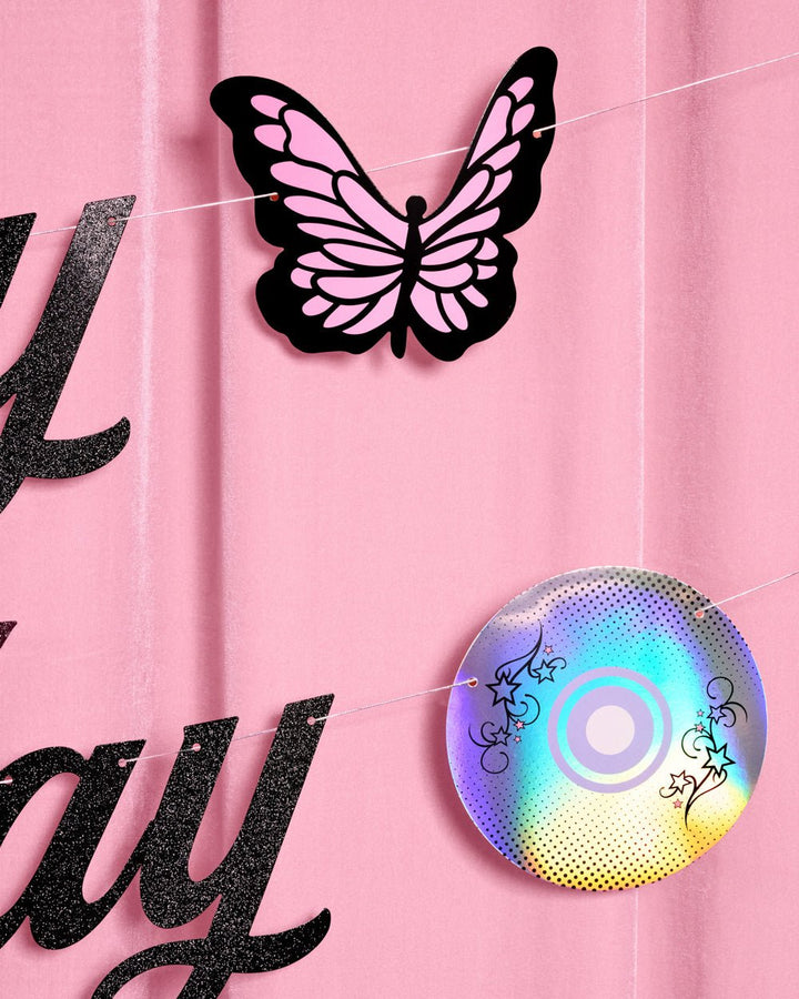 Pink and black butterfly cutout and iridescent CD icon from the Y2K birthday banner against pink curtains
