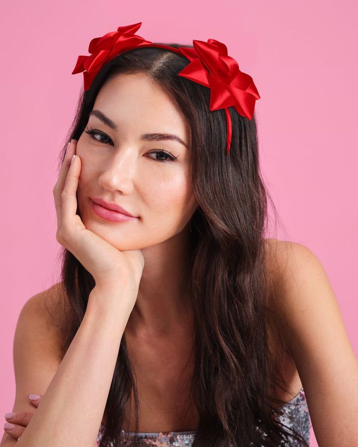 Woman wearing the red satin gift bow headband for a Christmas party photo