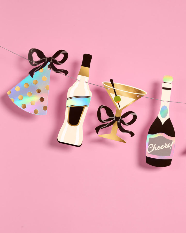Close-up of the New Year foil banner’s party hat, bottles, and martini glass with printed black bow details.