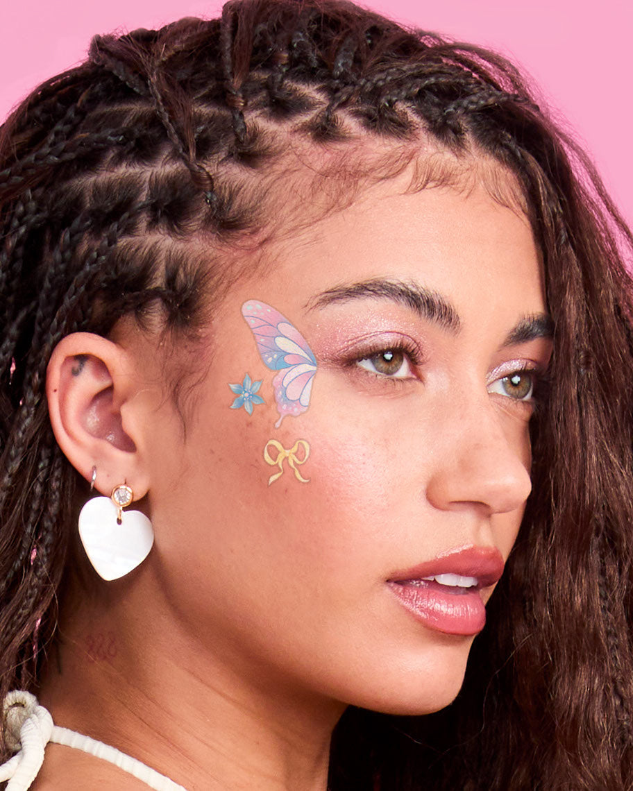 Lavender butterfly and flower face tattoos worn at the temple with a white heart earring