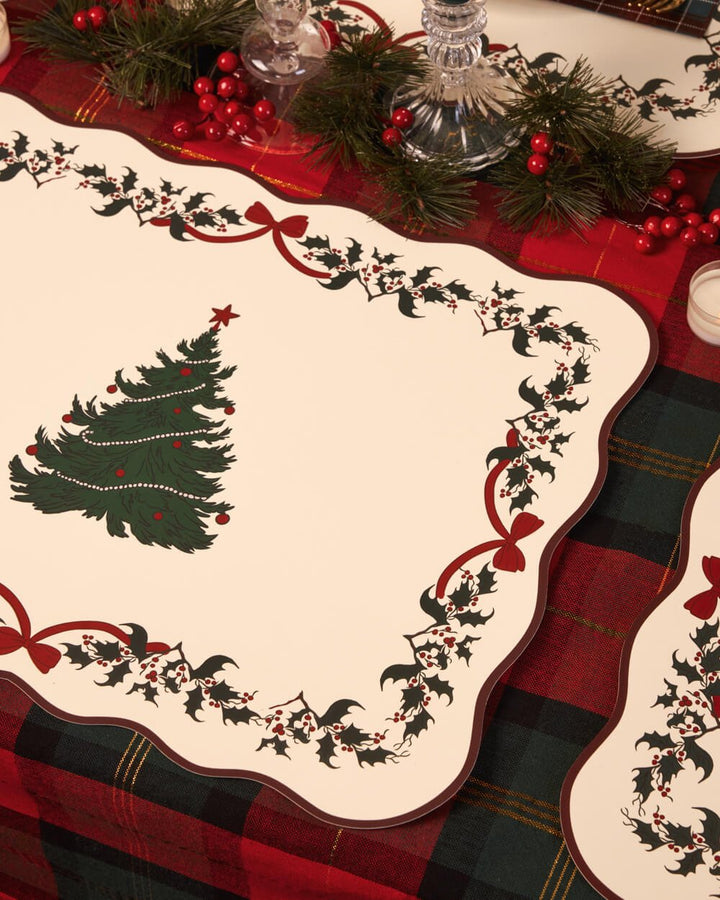 Christmas tree placemat on red tartan with greenery and berries alongside