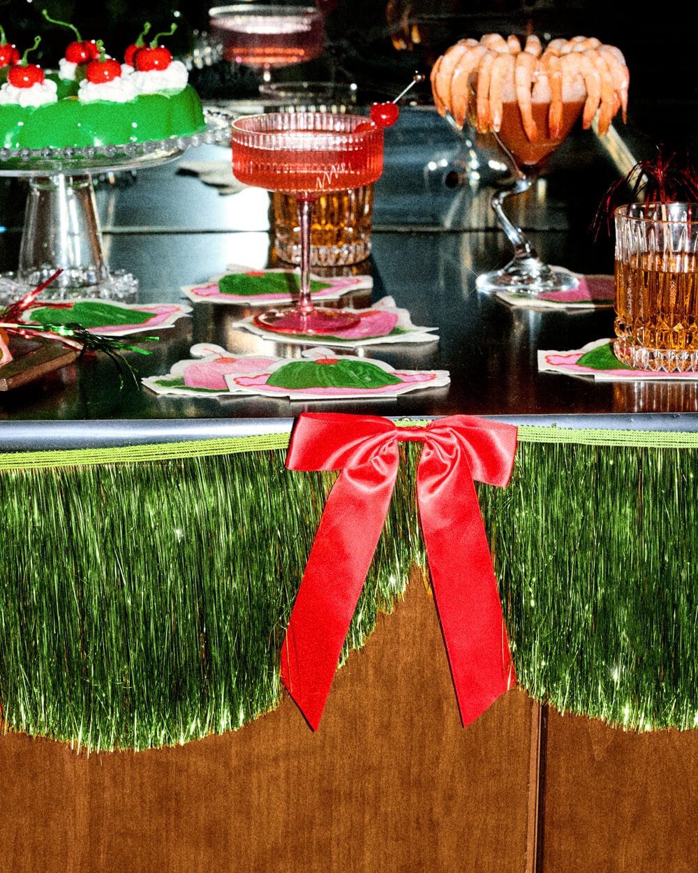Holiday bar styled with drinks and the green fringe banner along the front edge