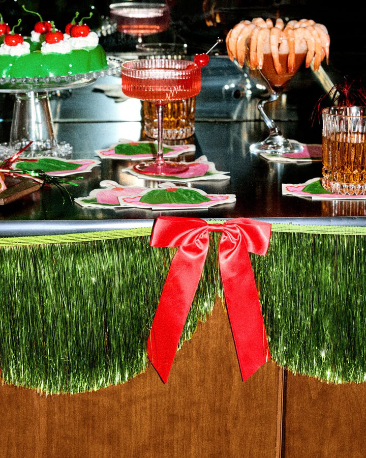 Holiday bar styled with drinks and the green fringe banner along the front edge