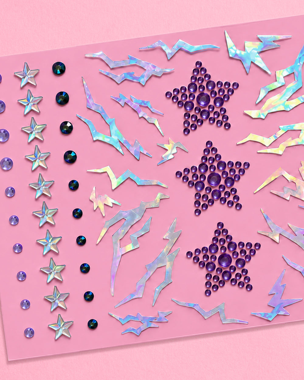 Close-up of purple star clusters, silver stars, round gems, and iridescent lightning face stickers.
