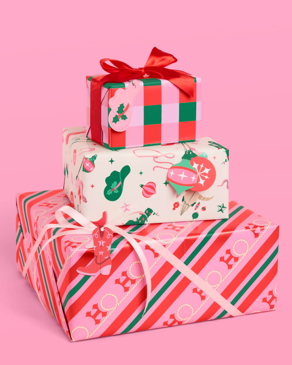 Western Christmas gift boxes wrapped in cowboy boot, cactus, gingham, and candy stripe paper in pink, red, and green.
