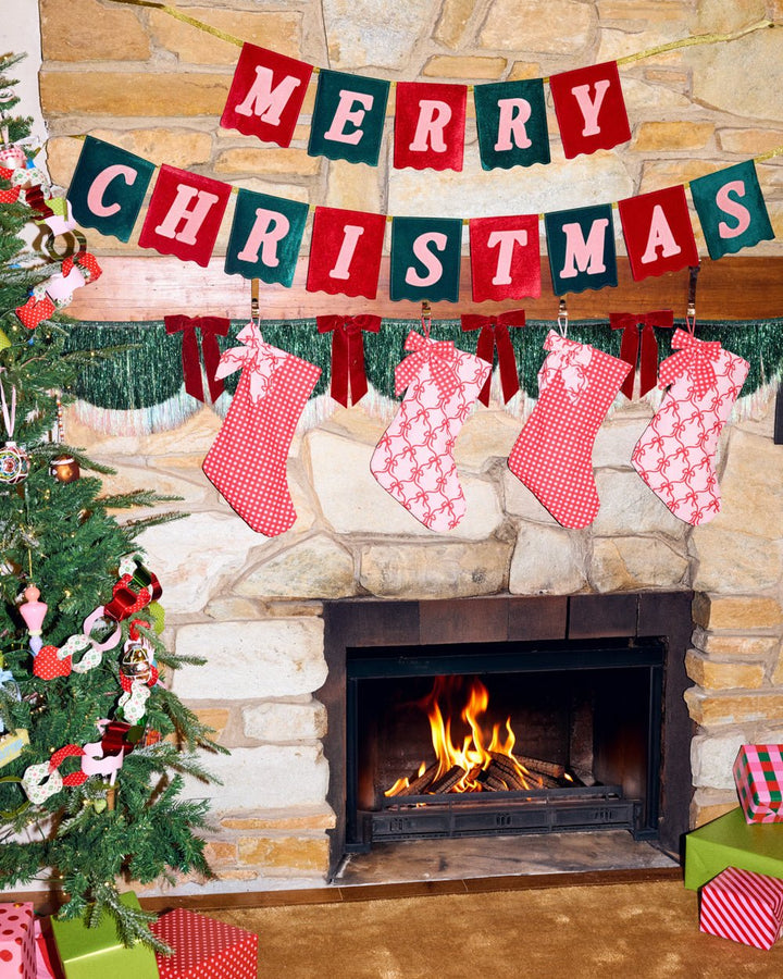 Merry Christmas velvet banner hung above a pink styled holiday table