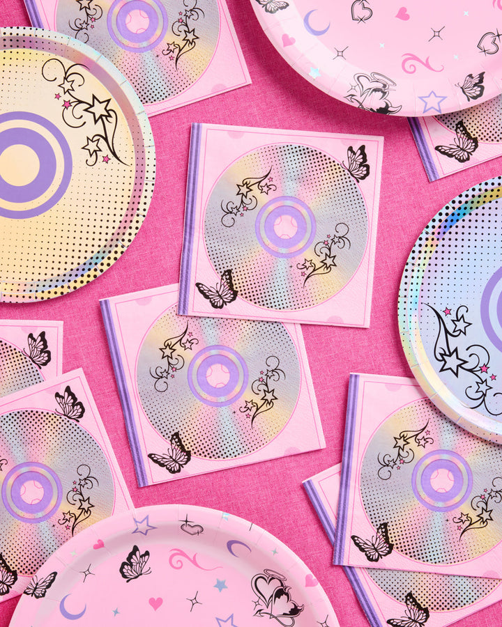 Stack of Y2K CD print cocktail napkins with an iridescent party plate on a pink table