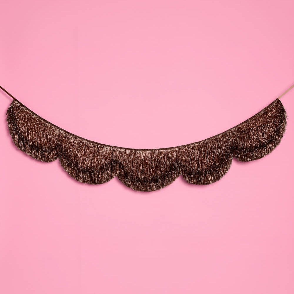 Espresso brown scalloped fringe banner curved across a pink wall as a party backdrop
