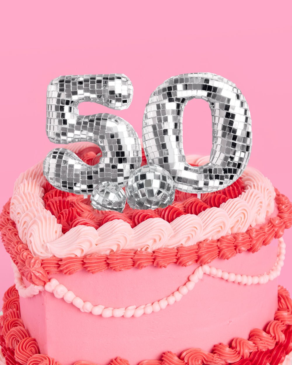 Silver mirrored 50 disco ball cake topper on a pink background