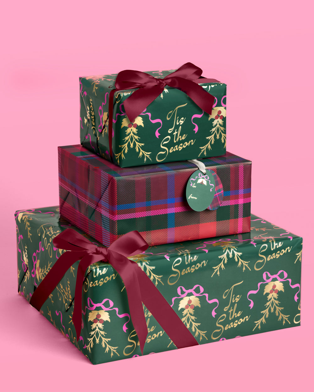 Christmas presents wrapped in deep green holly paper and tartan plaid, tied with red and green ribbon.