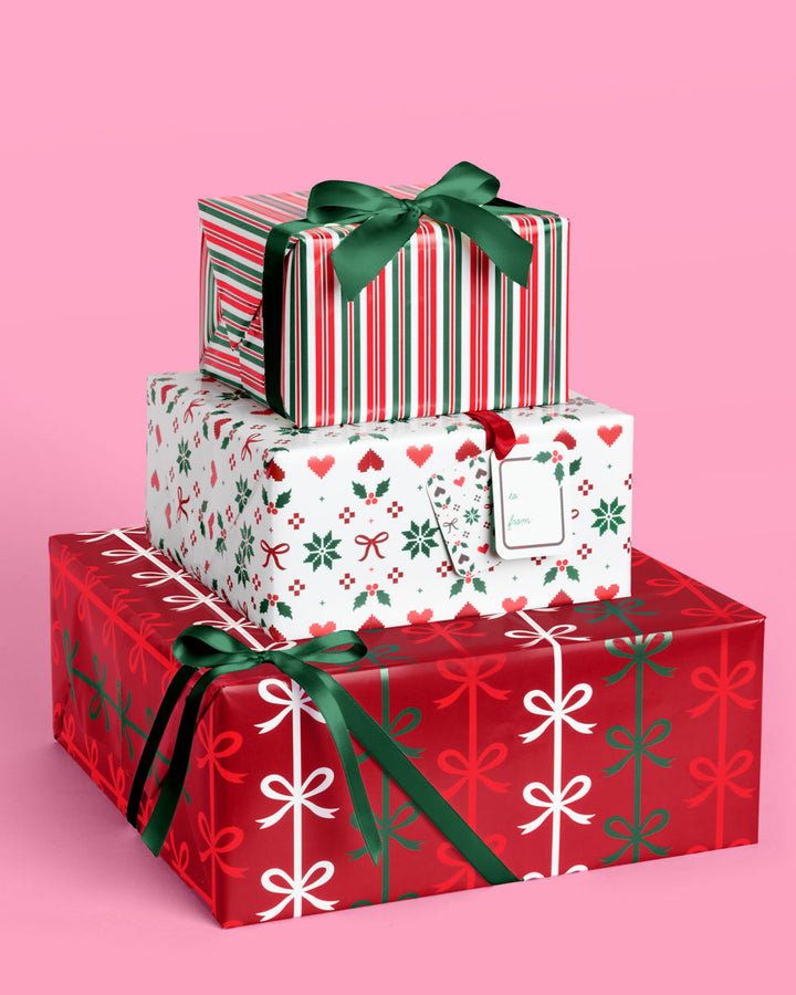 Christmas gifts wrapped in red, white, and green paper with snowflakes, holly, and candy stripe, tied with green ribbon.