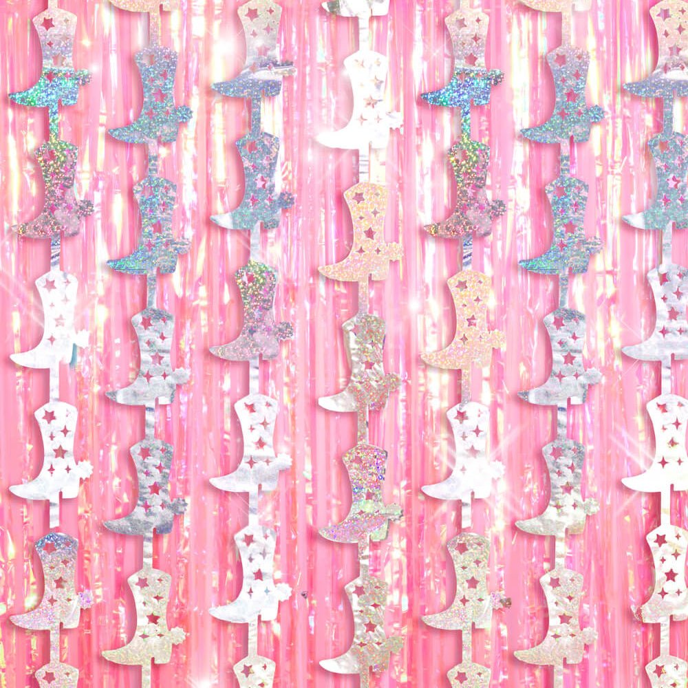 Holographic cowboy boot strands hanging over a pink foil fringe curtain for a cowgirl birthday party