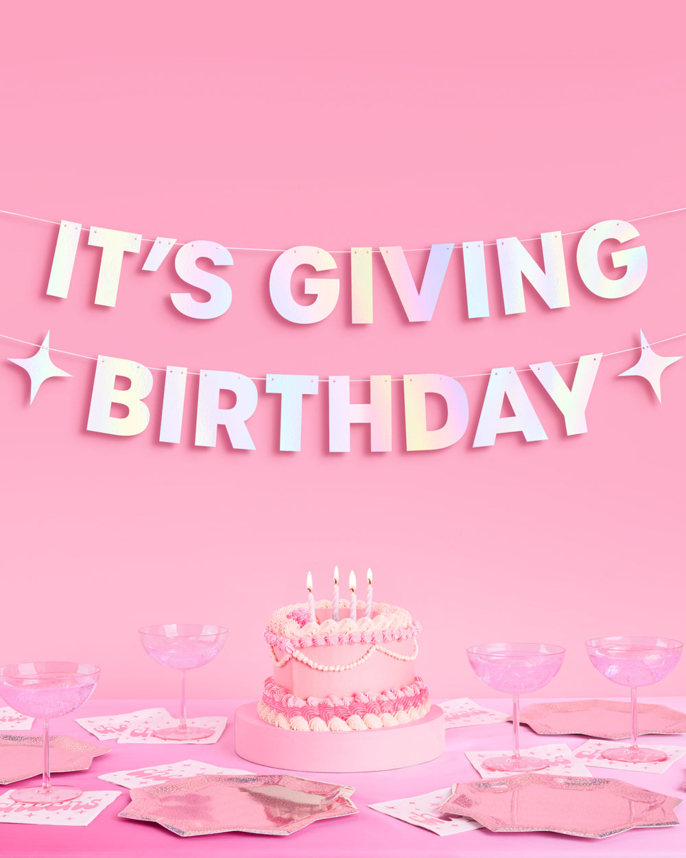 It's Giving Birthday iridescent foil banner hung above a pink birthday cake