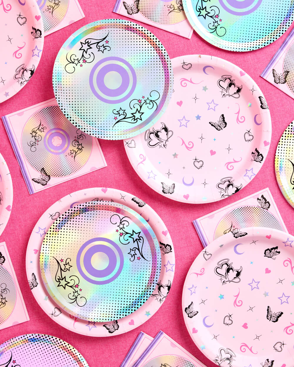 Y2K CD and butterfly paper plates stacked with napkins on a pink party table