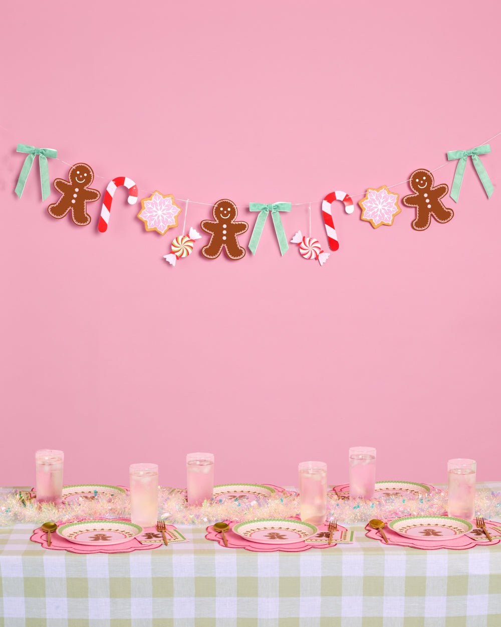 Gingerbread garland strung with peppermints, candy canes, and pink snowflakes on pink