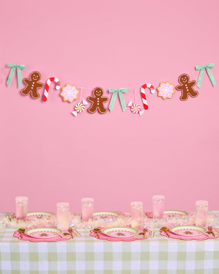 Gingerbread garland strung with peppermints, candy canes, and pink snowflakes on pink